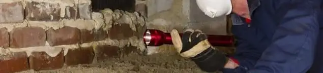 Pest control technician inspecting a crawl space for ant activity and entry points in Gilbert, AZ