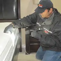 Bed bug inspection technician checking a mattress and bed frame for signs of infestation in Gilbert, AZ