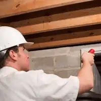 Termite inspection technician checking a basement wall and framing for termite activity in Gilbert, AZ
